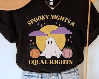 Könnte beinhalten: Schwarzes T-Shirt mit einem Grafikdruck eines Geistes, Kürbissen und eines Mondes mit dem Text "Spooky Nights & Equal Rights".