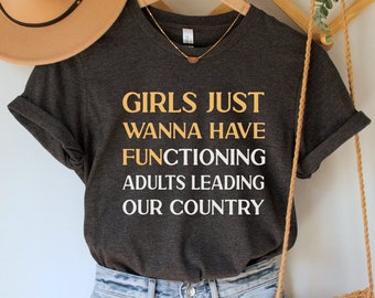 May include: A dark gray t-shirt with the text "Girls just wanna have functioning adults leading our country" printed in yellow.