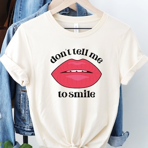May include: A white t-shirt with a red lips graphic and the text "don't tell me to smile".