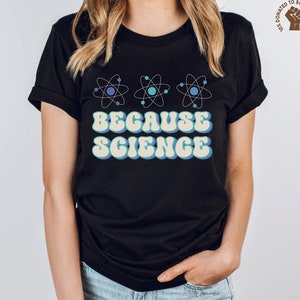 May include: Black t-shirt with a retro-style graphic of three blue and white atoms and the text "Because Science".
