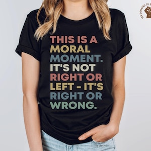 May include: Black t-shirt with the text "THIS IS A MORAL MOMENT. IT'S NOT RIGHT OR LEFT - IT'S RIGHT OR WRONG." in colorful retro-style lettering. The shirt also features a small graphic of a fist and the text "DONATED TO SOCIAL JUSTICE."