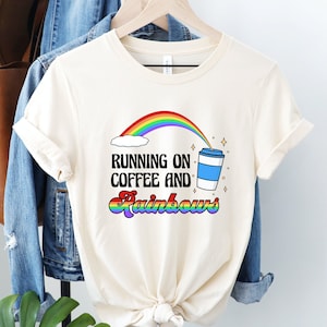 May include: A white t-shirt with a rainbow, a coffee cup, and the text "Running on Coffee and Rainbows".