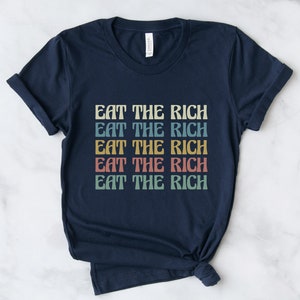 A navy blue unisex crew neck short sleeve Bella Canvas t-shirt that says "eat the rich" repeated 5 times in retro font and colors