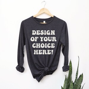 May include: A dark gray long-sleeved t-shirt with the text "DESIGN OF YOUR CHOICE HERE!" in white.