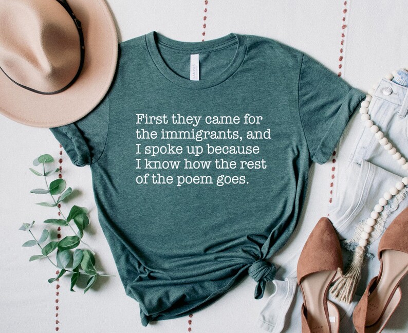 A heather forest green unisex short sleeve crew neck t-shirt that says "First they came for the immigrants, and I spoke up because I know how the rest of the poem goes." in white typewriter font on the chest.