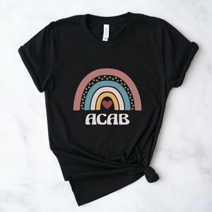 May include: Black t-shirt with a rainbow design and the text "ACAB" in white.