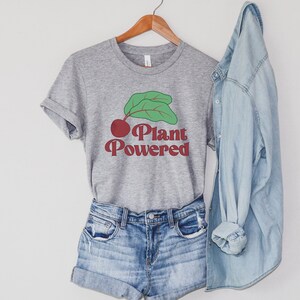 May include: A gray t-shirt with a red and green graphic of a beet with the text "Plant Powered" in red.