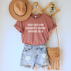 A heather mauve unisex crew neck short sleeve Bella Canvas t-shirt that says "vote like your children's future depends on it" in white chalkboard font