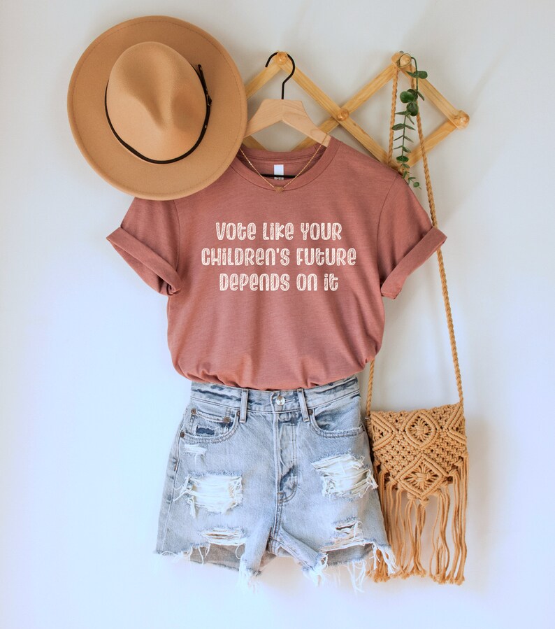 A heather mauve unisex crew neck short sleeve Bella Canvas t-shirt that says "vote like your children's future depends on it" in white chalkboard font