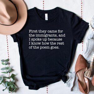 A black unisex short sleeve crew neck t-shirt that says "First they came for the immigrants, and I spoke up because I know how the rest of the poem goes." in white typewriter font on the chest.