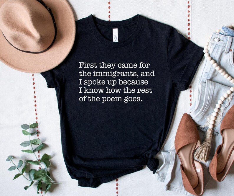 A black unisex short sleeve crew neck t-shirt that says "First they came for the immigrants, and I spoke up because I know how the rest of the poem goes." in white typewriter font on the chest.