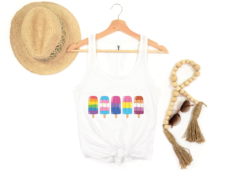 Pu&ograve; includere: Canotta bianca con una grafica di cinque ghiaccioli arcobaleno. I ghiaccioli sono disposti in fila e ognuno ha uno schema di colori diverso che rappresenta diverse bandiere pride.