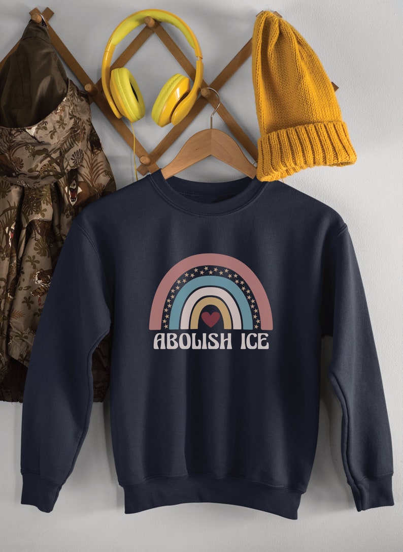 May include: A navy blue sweatshirt with a rainbow graphic and the text "Abolish ICE" in white. A red heart is in the center of the rainbow.