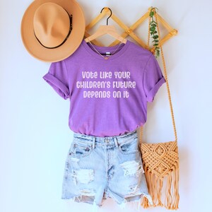 A heather team (medium) purple unisex crew neck short sleeve Bella Canvas t-shirt that says "vote like your children's future depends on it" in white chalkboard font