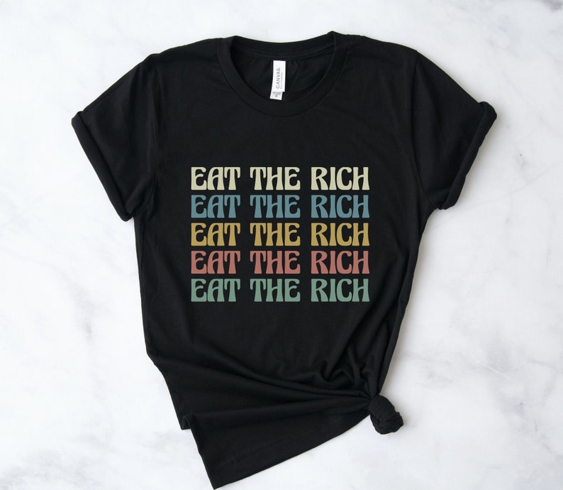 A black unisex crew neck short sleeve Bella Canvas t-shirt that says "eat the rich" repeated 5 times in retro font and colors