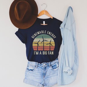 May include: A navy blue t-shirt with a vintage-style graphic of wind turbines and the text "Renewable Energy I'm a Big Fan".