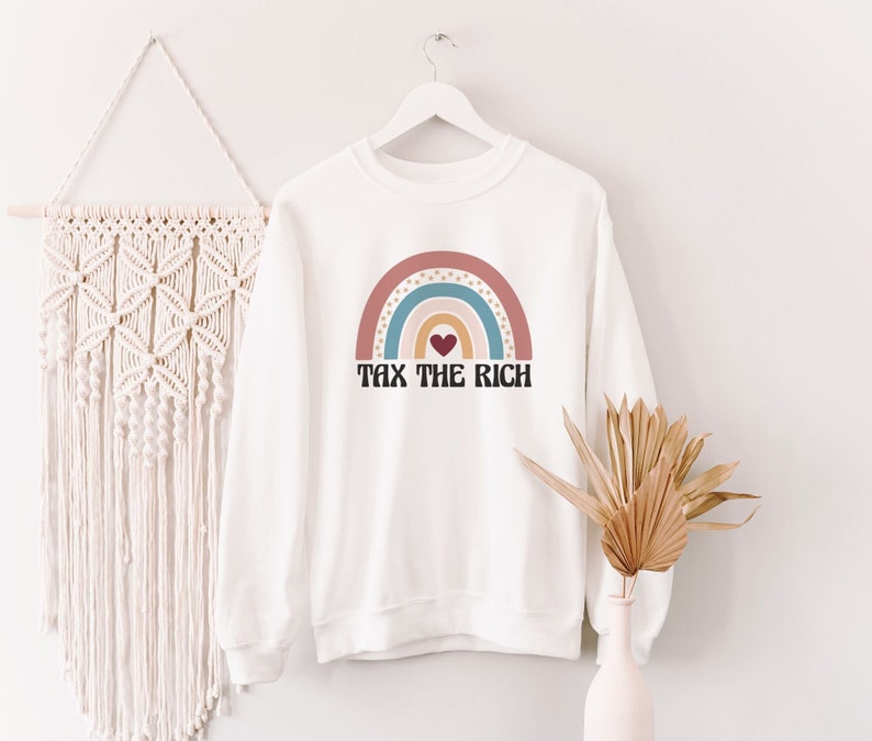May include: White sweatshirt with a rainbow graphic and the text "Tax the Rich" in black letters. A small red heart is in the center of the rainbow.
