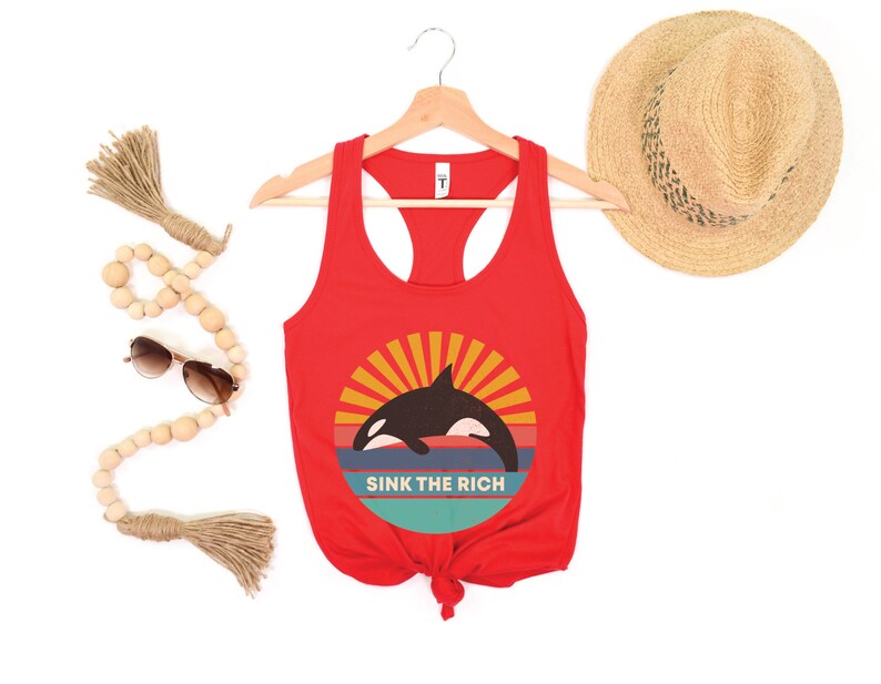 A red women's racerback tank top that says "sink the rich" in white over a retro graphic of an orca whale in the ocean