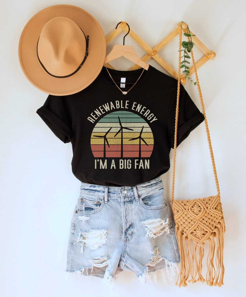 May include: Black t-shirt with a vintage-style graphic of wind turbines and a sunset. The text "Renewable Energy I'm a Big Fan" is printed on the shirt.