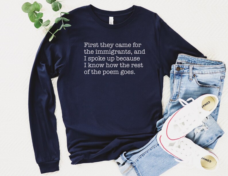 A navy blue unisex long sleeve crew neck t-shirt that says "First they came for the immigrants, and I spoke up because I know how the rest of the poem goes." in white typewriter font on the chest.