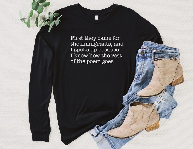 A black unisex long sleeve crew neck t-shirt that says "First they came for the immigrants, and I spoke up because I know how the rest of the poem goes." in white typewriter font on the chest.