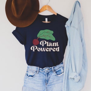 May include: A navy blue t-shirt with a green leaf and red beet graphic and the text "Plant Powered" in a retro font.