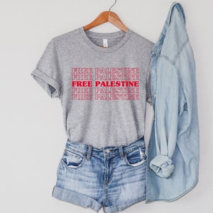 An athletic (medium grey) heather unisex crew neck t-shirt with red text saying "Free Palestine" 5 times, with the middle text full red and the top and bottom 2 just a red outline