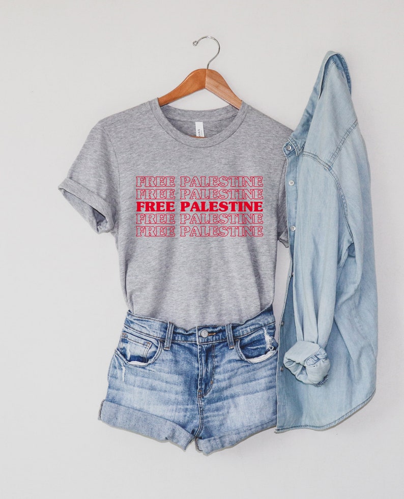 An athletic (medium grey) heather unisex crew neck t-shirt with red text saying "Free Palestine" 5 times, with the middle text full red and the top and bottom 2 just a red outline