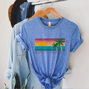 May include: A blue t-shirt with a retro sunset graphic and palm trees. The text "RESPECT IT. PROTECT IT" is printed below the graphic.
