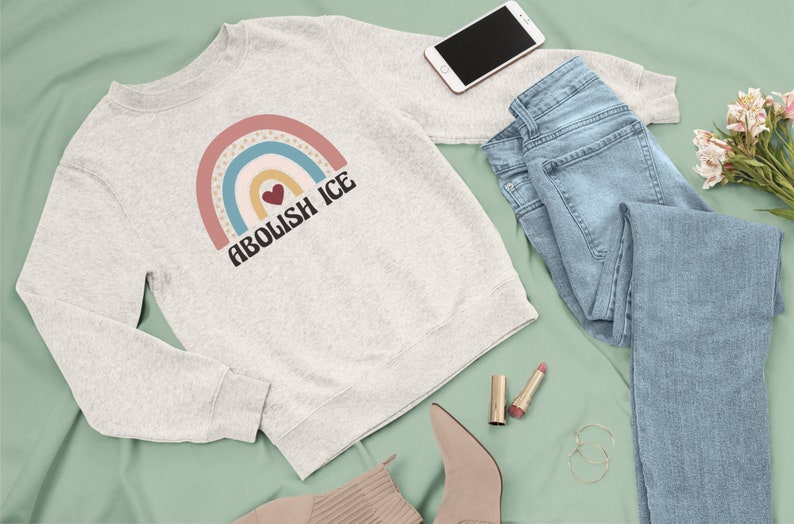 May include: A grey sweatshirt with a rainbow graphic and the text "Abolish ICE" in black. A heart is in the center of the rainbow.
