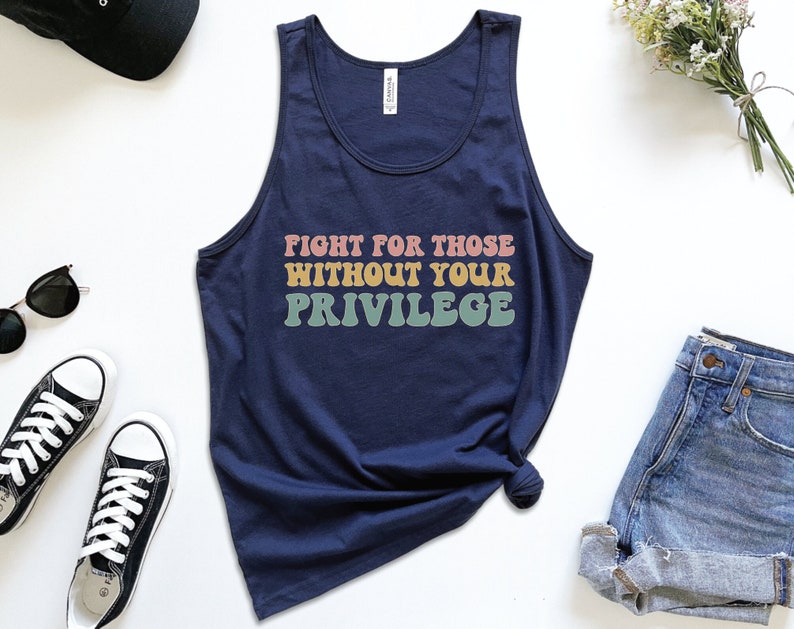 A navy blue unisex scoop neck Bella Canvas tank top that says "fight for those without your privilege" in peach, yellow, and green text with a white outline