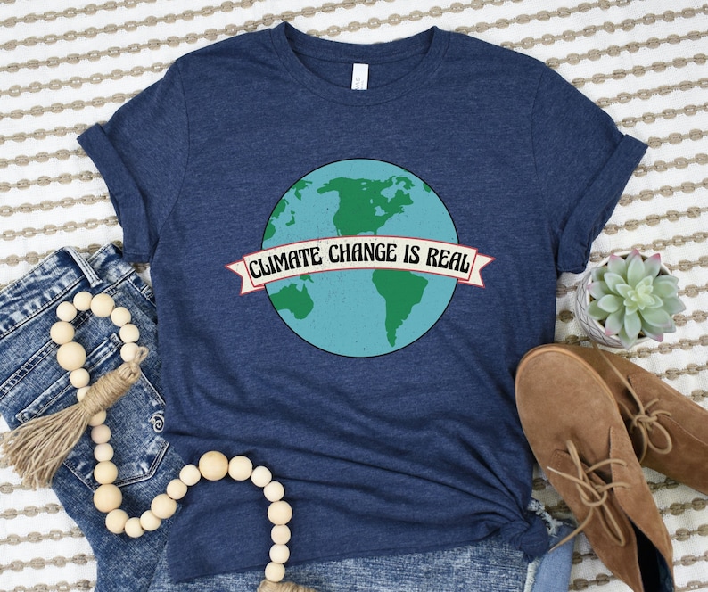 May include: A navy blue t-shirt featuring a graphic of the Earth and the text "Climate Change is Real" on a banner.
