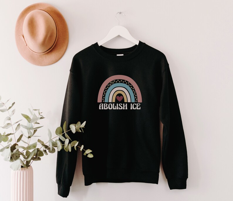 May include: Black sweatshirt with a rainbow graphic and the text "Abolish ICE" in white.