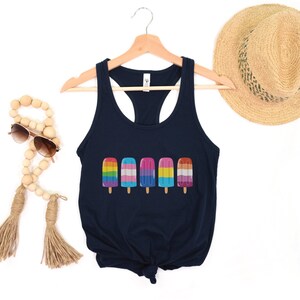 Pu&ograve; includere: Un top a canotta blu navy con un design di ghiaccioli con i colori dell'arcobaleno, della bandiera transgender e della bandiera bisessuale. Il top &egrave; su un appendiabiti e ha uno stile racerback.