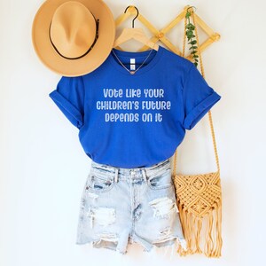 A royal blue unisex crew neck short sleeve Bella Canvas t-shirt that says "vote like your children's future depends on it" in white chalkboard font