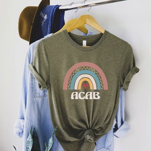 May include: A green t-shirt with a rainbow graphic and the text "ACAB" in a retro font. The rainbow has a red heart in the center.