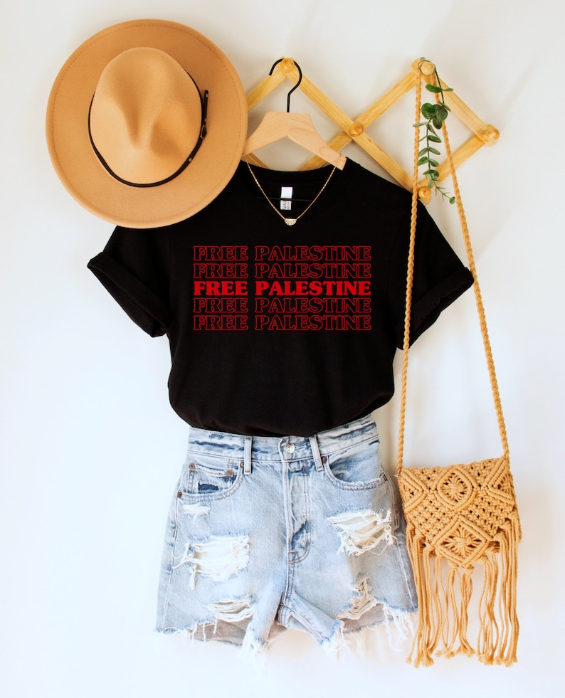 A black unisex crew neck t-shirt with red text saying "Free Palestine" 5 times, with the middle text full red and the top and bottom 2 just a red outline