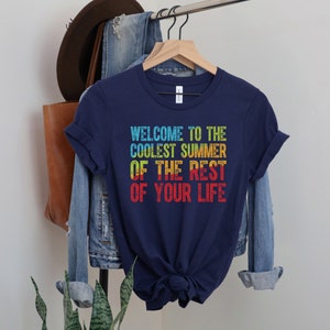 A navy blue crew neck short sleeve unisex t-shirt that says "welcome to the coolest summer of the rest of your life" with a blue, green, yellow and red heat map in the text