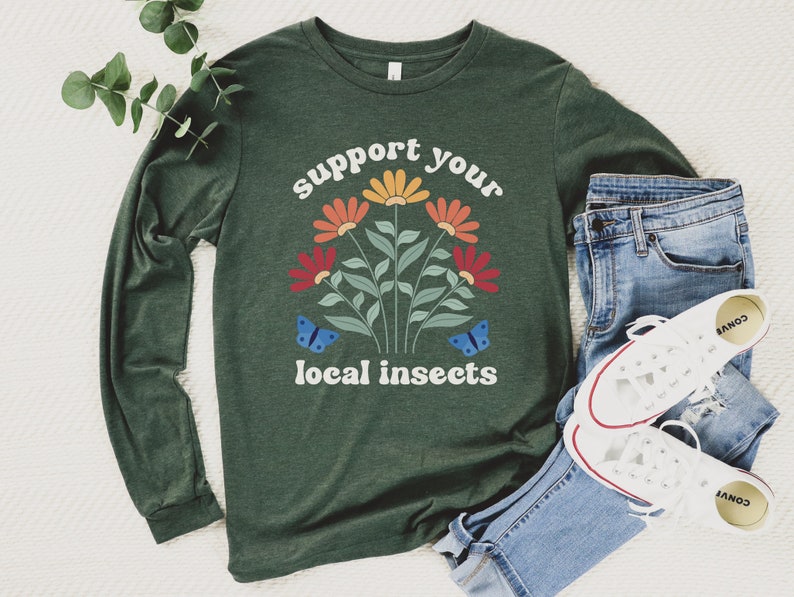 A heather forest green unisex long sleeve crew neck t-shirt with the words "support your local insects" in white text around an image of colorful flowers and butterflies