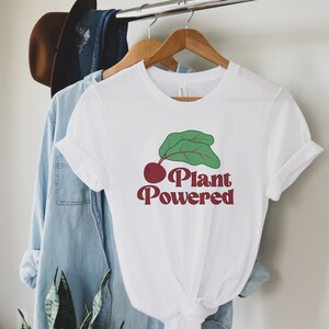 May include: White t-shirt with a red beet and green leaves graphic and the text "Plant Powered" in red.