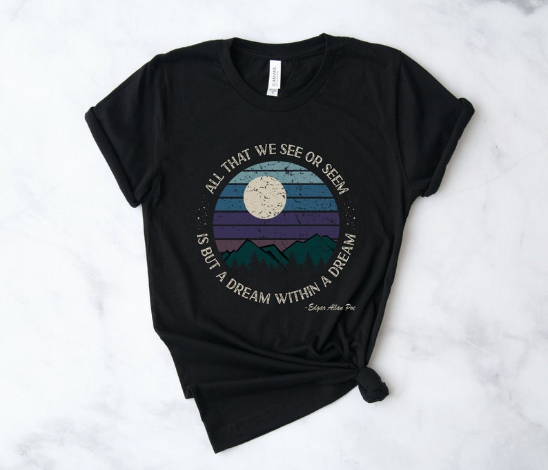 May include: Black t-shirt with a vintage-style graphic of a moon, mountains, and the quote "All that we see or seem is but a dream within a dream" by Edgar Allan Poe.