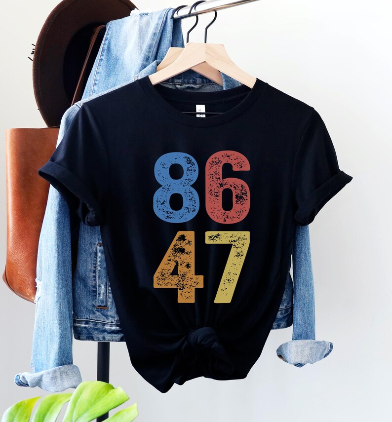 A black unisex crew neck short sleeve Bella+Canvas t-shirt that says "86 47" on the front in large bold distressed numbers, with a blue 8, red 6, orange 4, and yellow 7