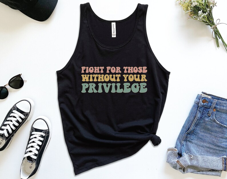 A black unisex scoop neck Bella Canvas tank top that says "fight for those without your privilege" in peach, yellow, and green text with a white outline