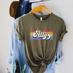 May include: A green t-shirt with a rainbow stripe and the word "Ally" in a retro font.