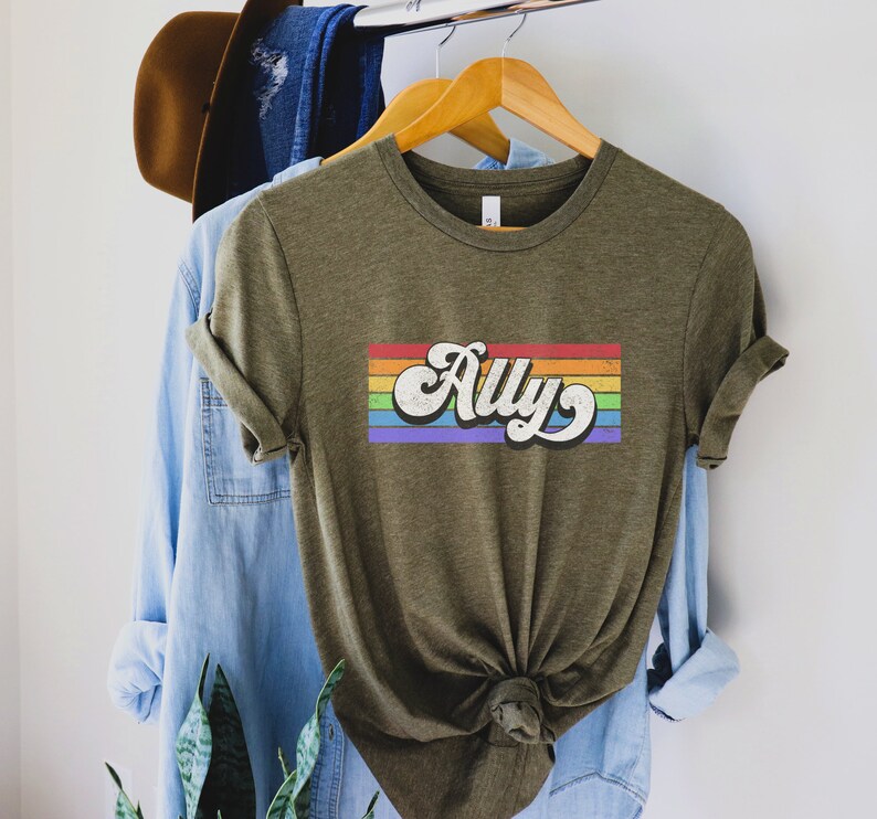 May include: A green t-shirt with a rainbow stripe and the word "Ally" in a retro font.