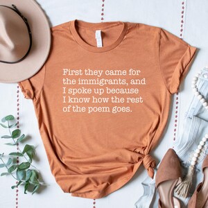 A heather autumn (dark orange) unisex short sleeve crew neck t-shirt that says "First they came for the immigrants, and I spoke up because I know how the rest of the poem goes." in white typewriter font on the chest.