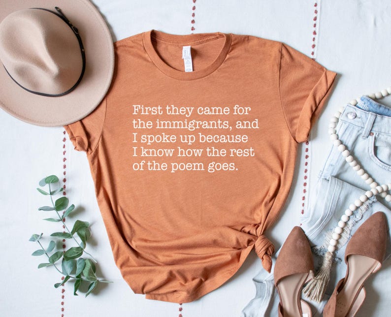 A heather autumn (dark orange) unisex short sleeve crew neck t-shirt that says "First they came for the immigrants, and I spoke up because I know how the rest of the poem goes." in white typewriter font on the chest.