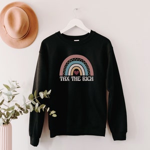 May include: Black sweatshirt with a rainbow graphic and the text "Tax the Rich" in white.