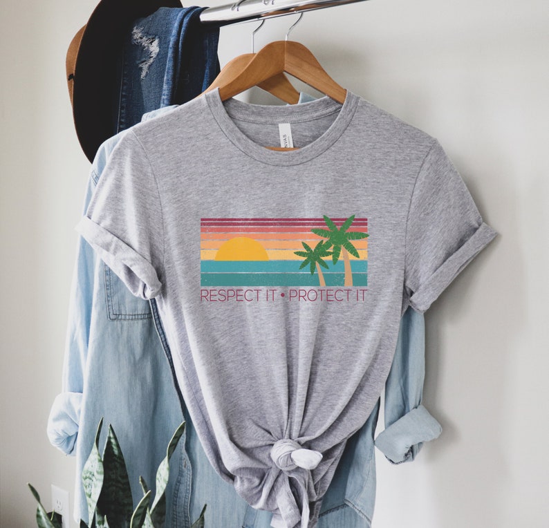 May include: Gray t-shirt with a retro sunset and palm trees graphic. The text "Respect It. Protect It." is printed below the graphic.