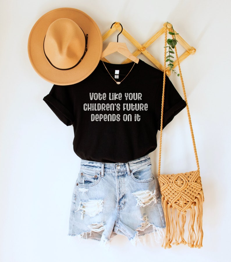 A black unisex crew neck short sleeve Bella Canvas t-shirt that says "vote like your children's future depends on it" in white chalkboard font